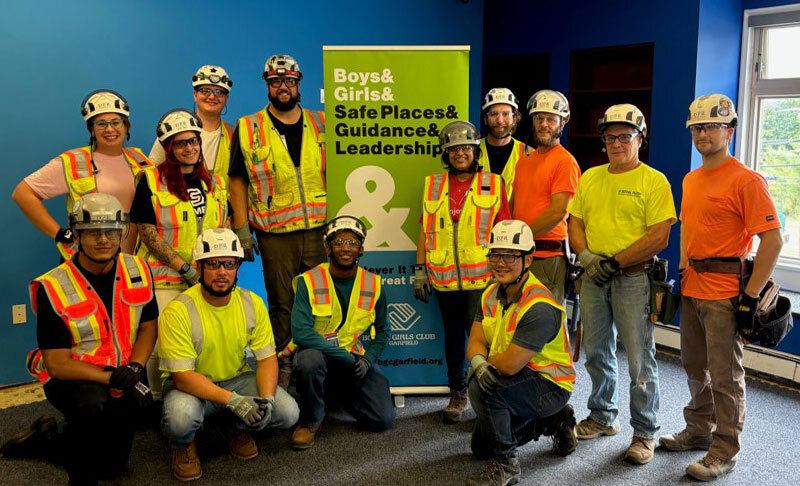 a group of volunteers posing with a Boys & Girls Club banner