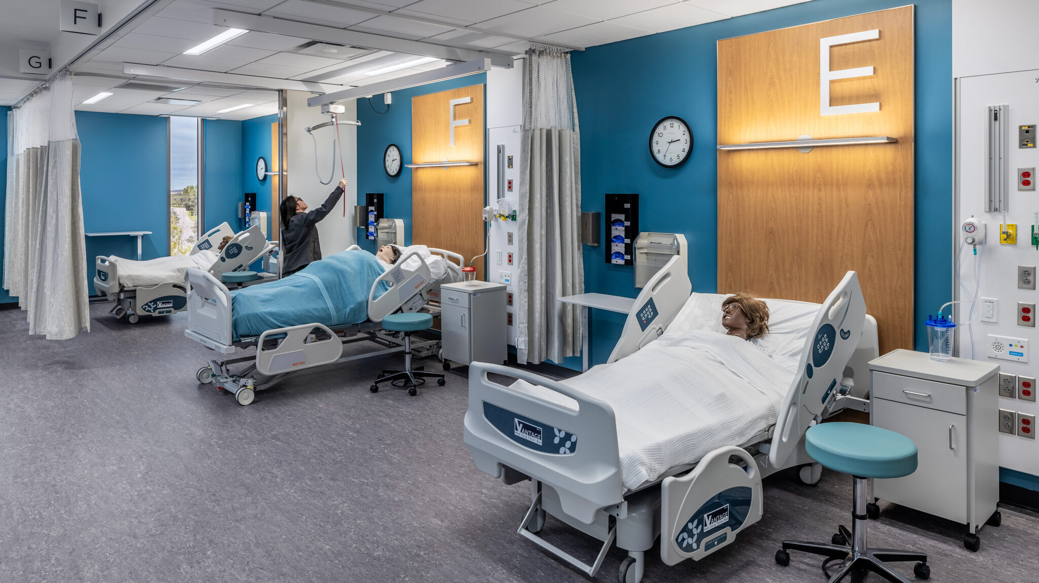 Nursing student using patient dummies in mock hospital bays